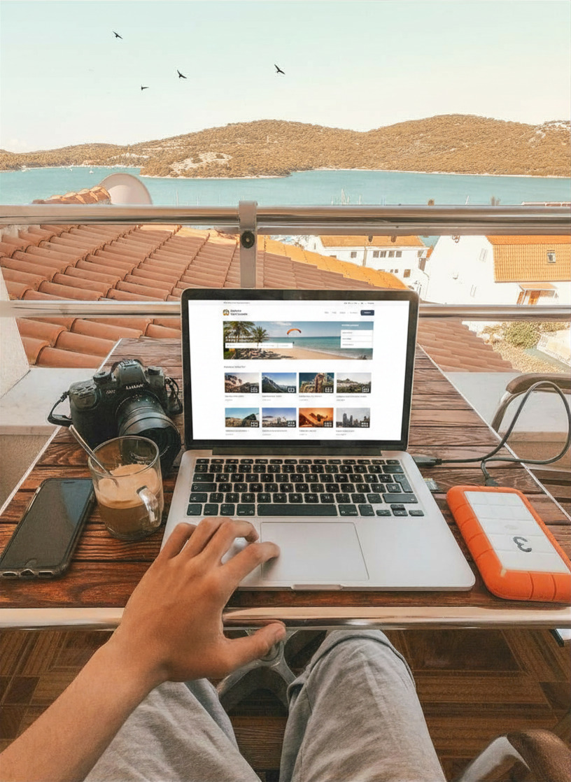 Traveler on a balcony overlooking a coastal town, booking tours and activities on a travel marketplace